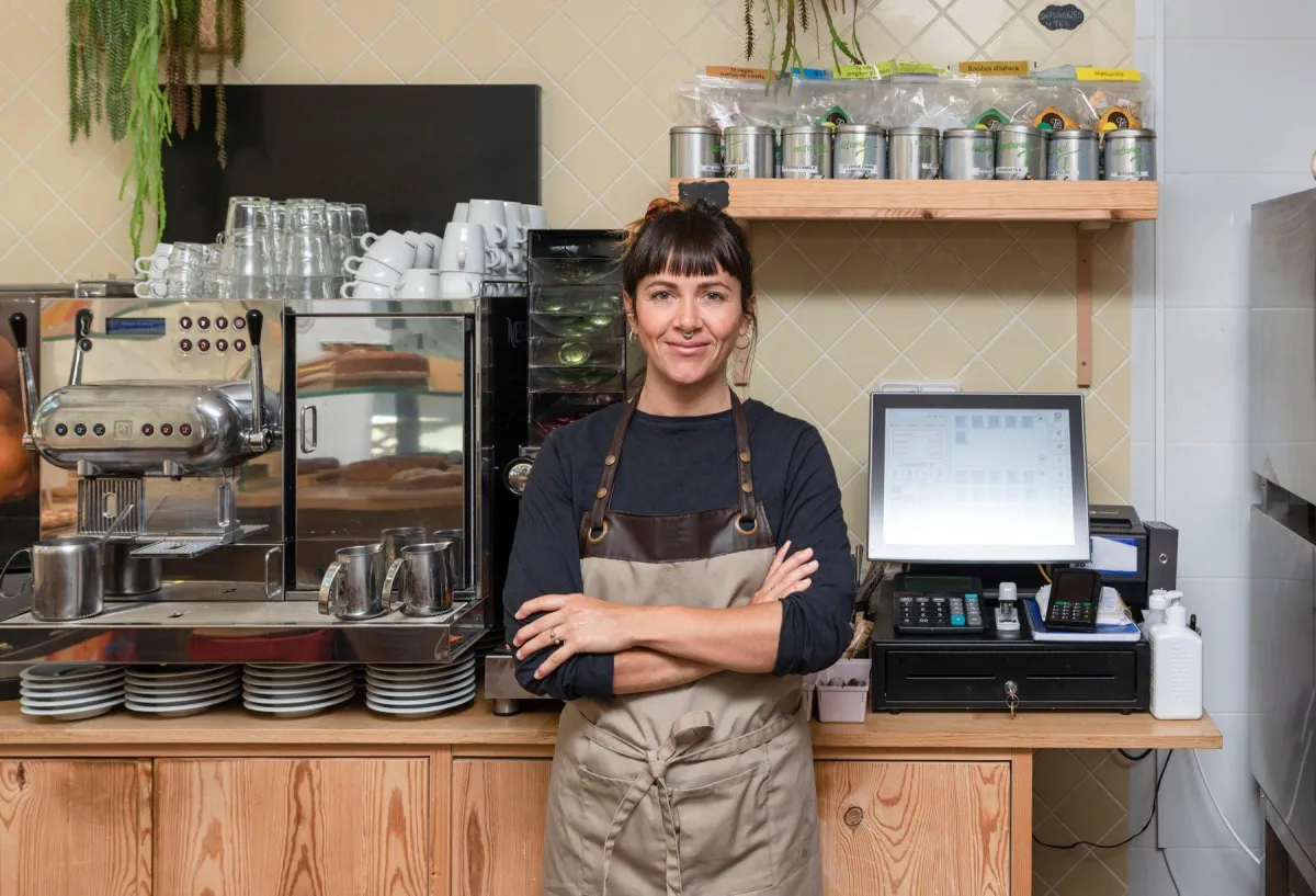 Sicherheitspakete für Unternehmen Inhaberin eines Cafés steht mit verschränkten Armen hinter ihrer Theke