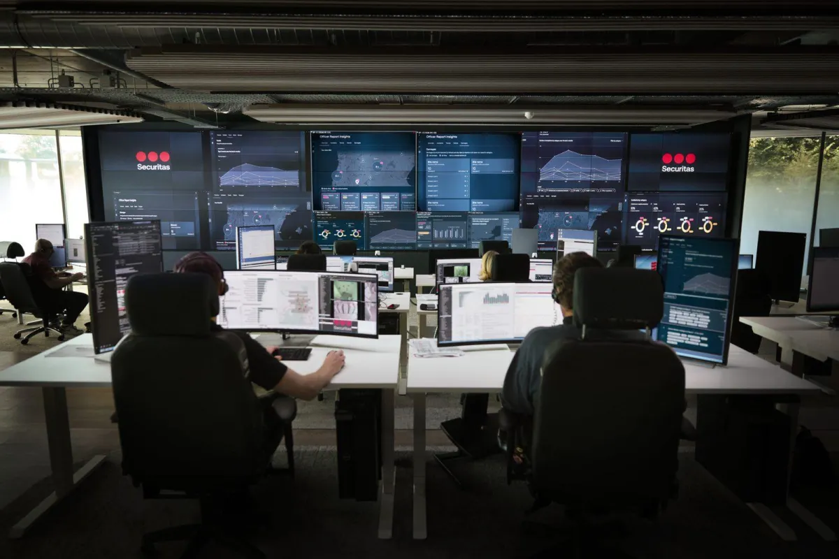 Mitarbeitende der Securitas-Leitstelle an ihren Arbeitsplätzen vor einer großen Monitorwand