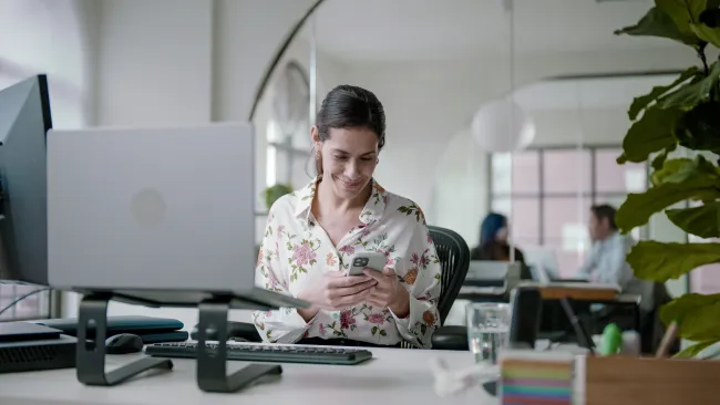 Einfache Bedienung per App Zufriedene Geschäftsfrau nutzt Securitas Connect App im Büro